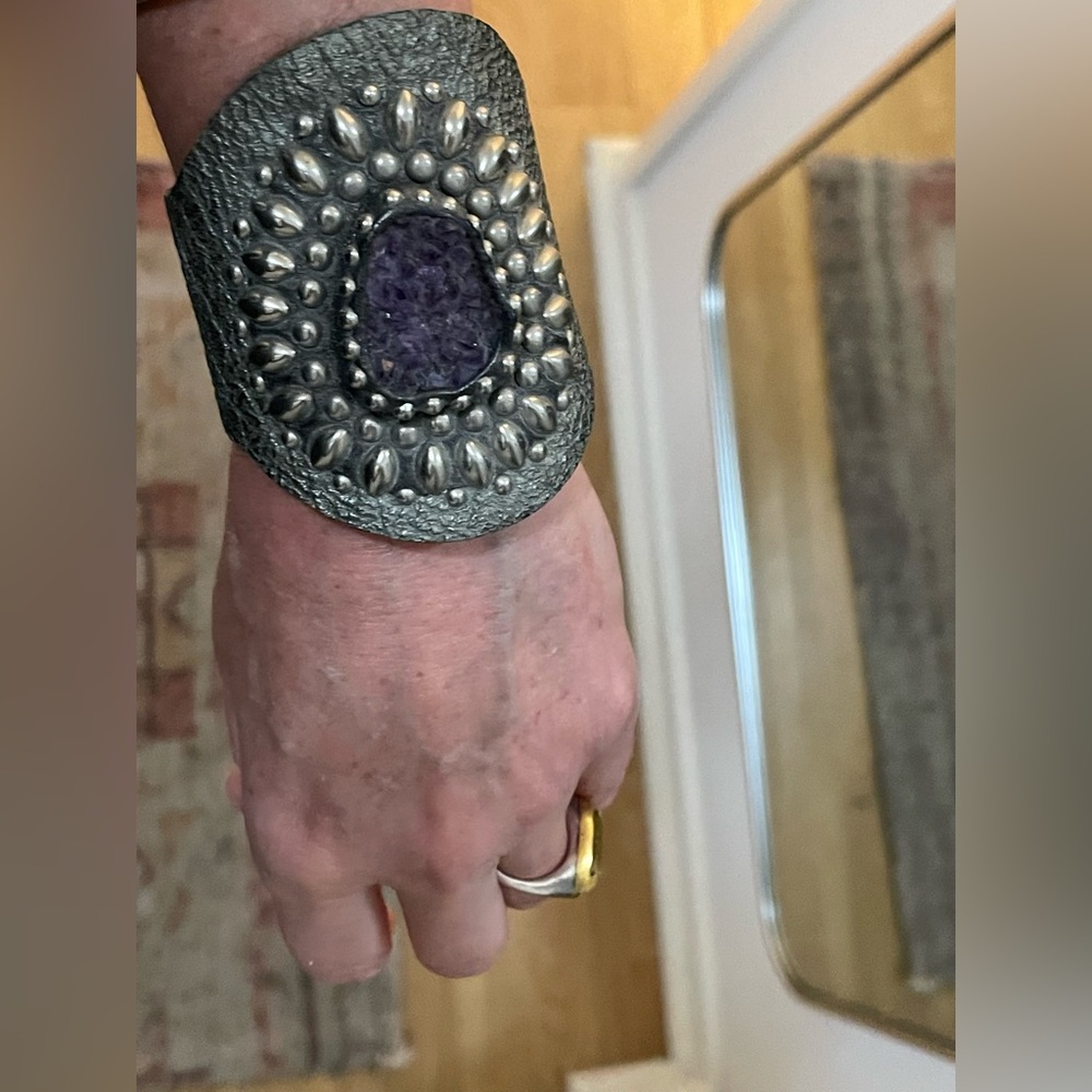 Wide silvery grey leather bracelet. Buckle closure.  Raw amethyst center piece.